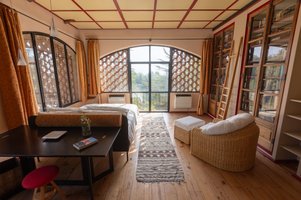 Biblioteca con librerie, poltrone e vetrata ad arco