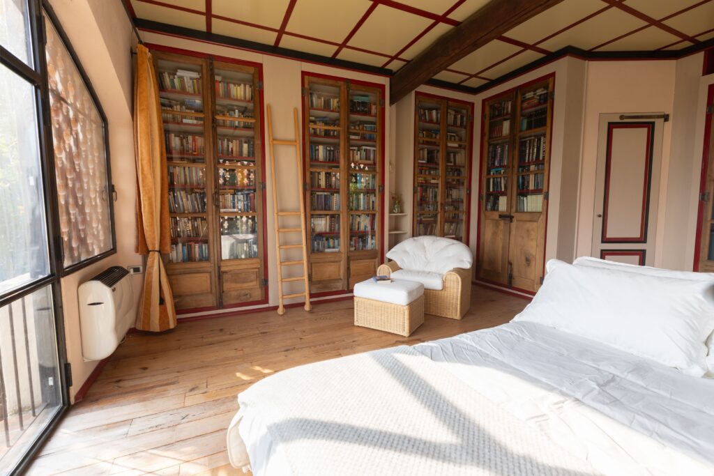 Biblioteca con librerie, poltrone e vetrata ad arco